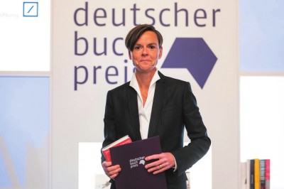 作家安特耶·拉维克·施特鲁贝尔在2021年德国图书奖颁奖典礼上手持《蓝色女人》和获奖证书。摄影:托马斯·洛内斯